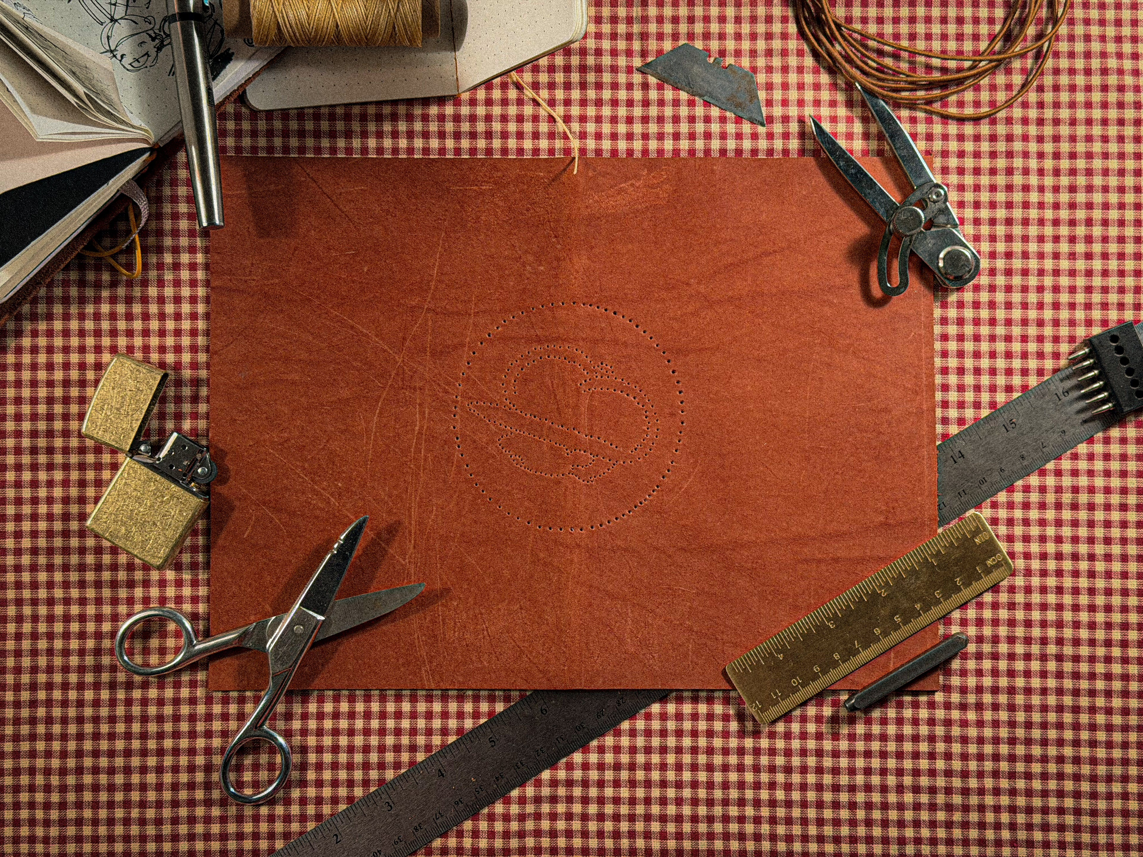 Leather crafting tools and materials on a checkered tablecloth