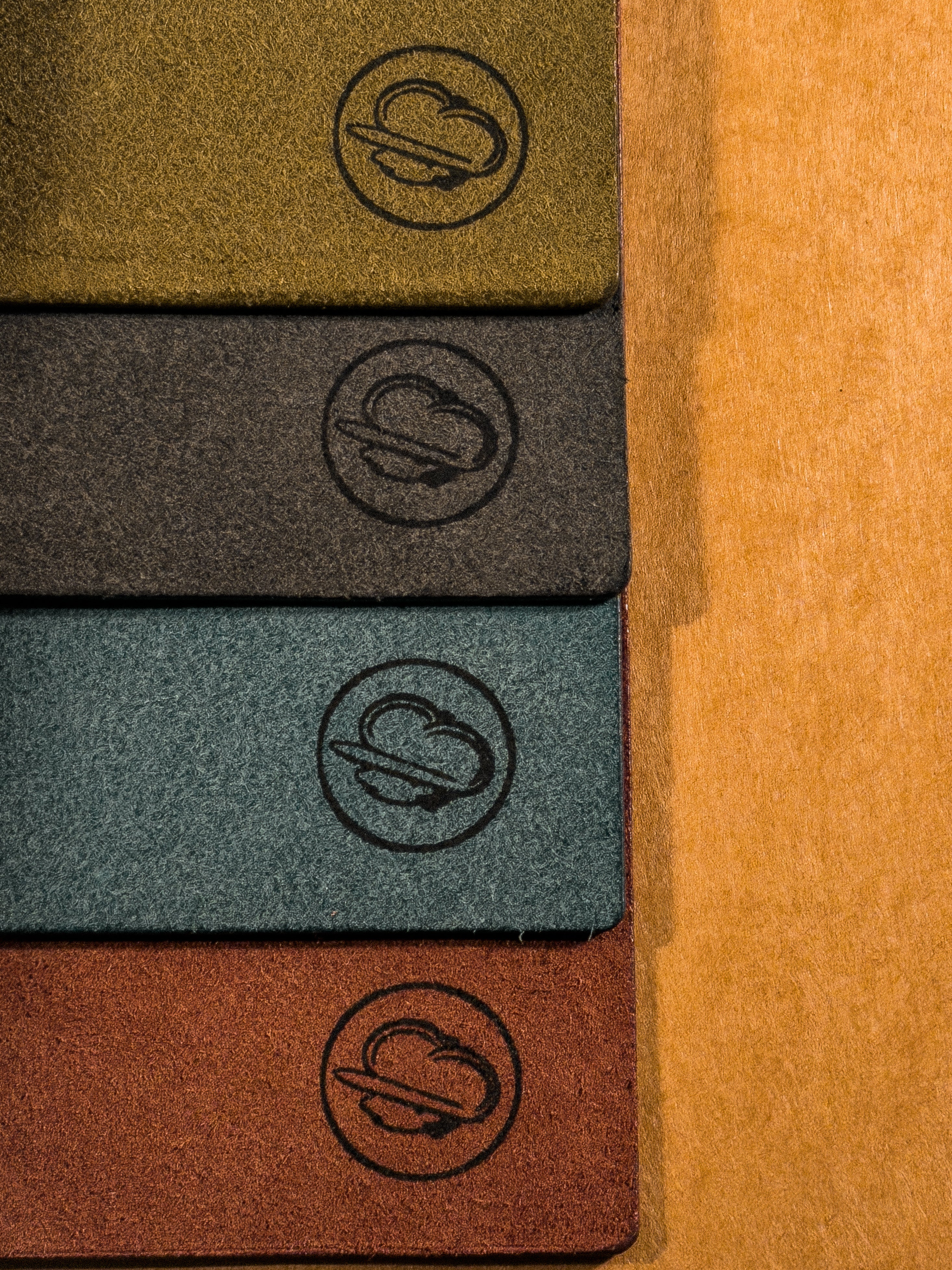 From top to bottom, green, black, blue, and brown interior bottom right corners of leather journals showcasing the paperboy leather makers mark