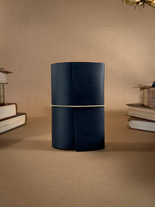 A pocket sized tri-fold blue leather journal on a beige background